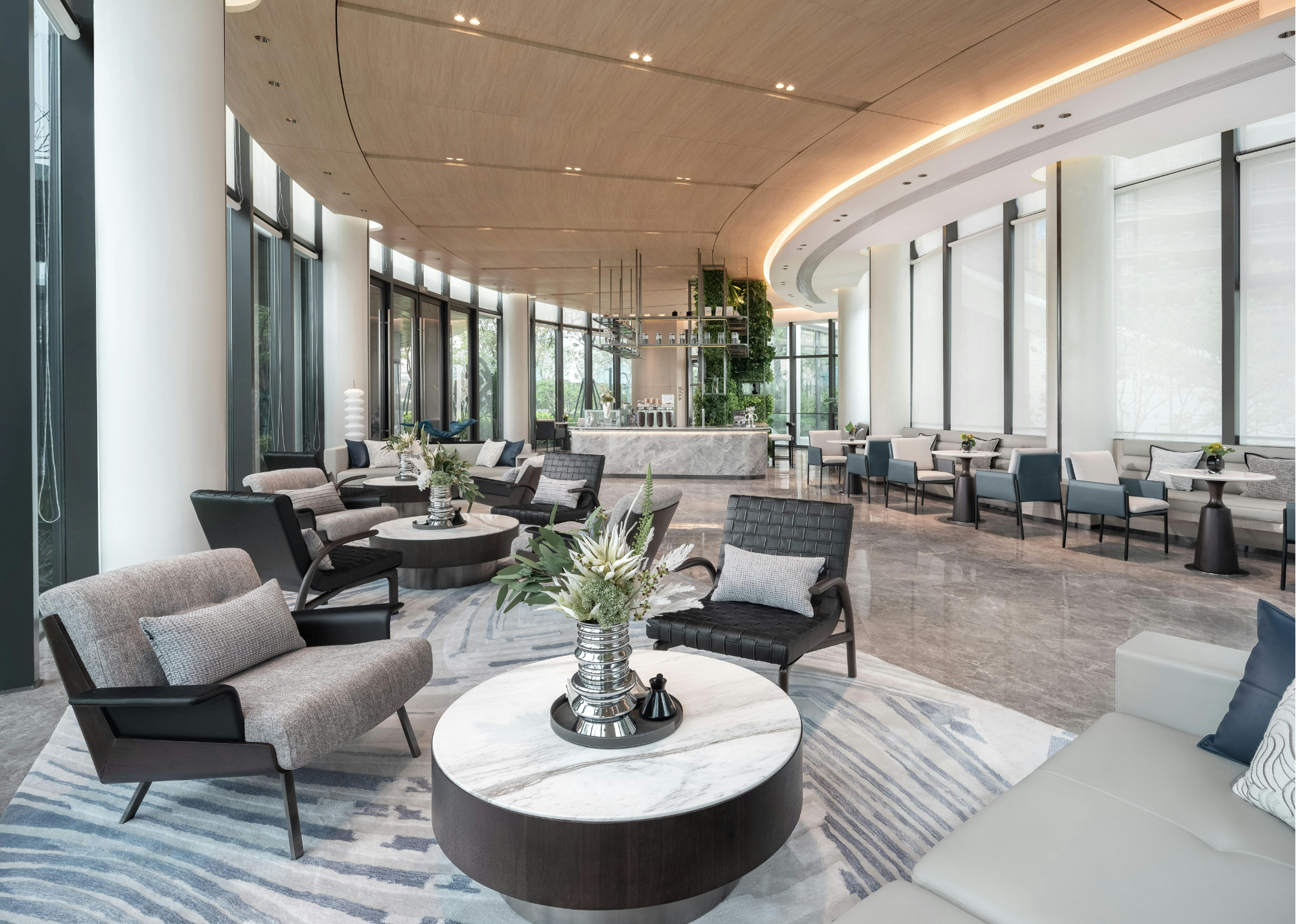 En modern och stilren hotell-lobby med fåtöljer och soffbord i neutrala färger.