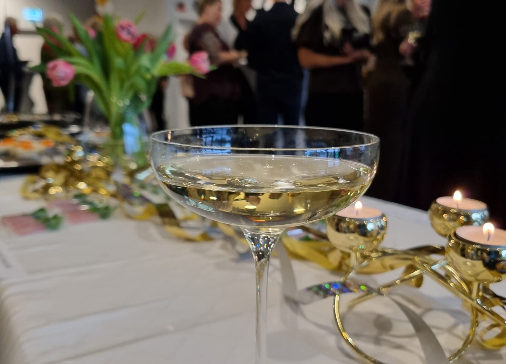 Ett festligt event, bord med en drink och människor i bakgrunden
